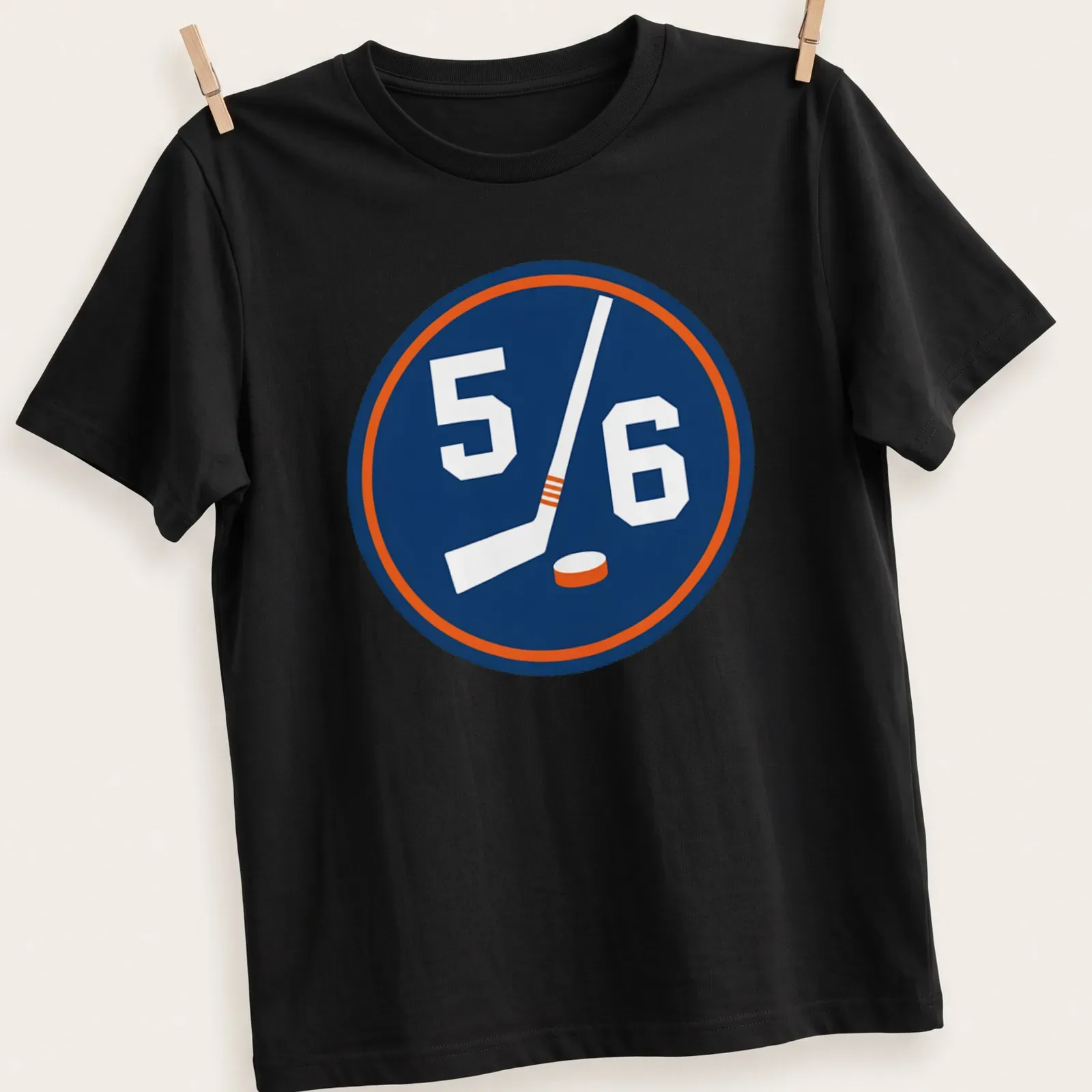 Hockey-themed shirt with a 5/6 emblem featuring a stick and puck in navy, white, and orange — printed on a unisex t-shirt