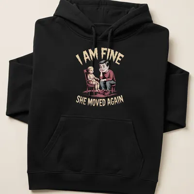 Humorous illustration of a father with a doll and text saying I AM FINE SHE MOVED AGAIN — printed on a unisex hoodie