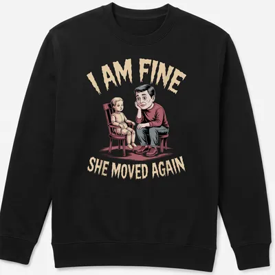 Humorous illustration of a father with a doll and text saying I AM FINE SHE MOVED AGAIN — printed on a unisex sweatshirt