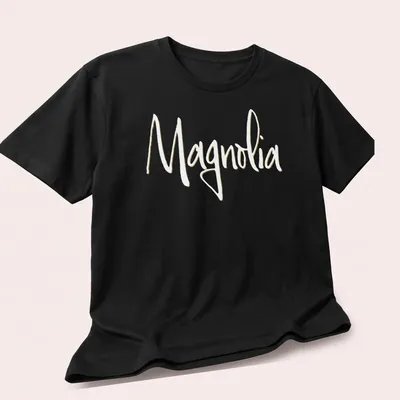 Elegant script reading 'Magnolia' in light yellow on a white background. — printed on a unisex t-shirt (angled view)