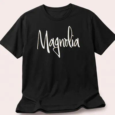 Elegant script reading 'Magnolia' in light yellow on a white background. — printed on a unisex t-shirt