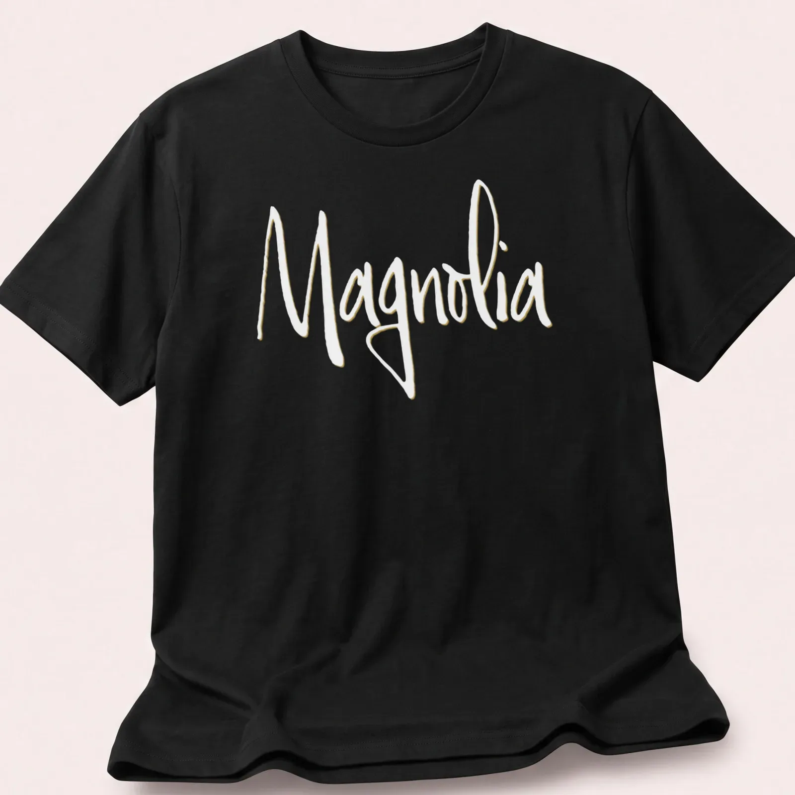 Elegant script reading 'Magnolia' in light yellow on a white background. — printed on a unisex t-shirt