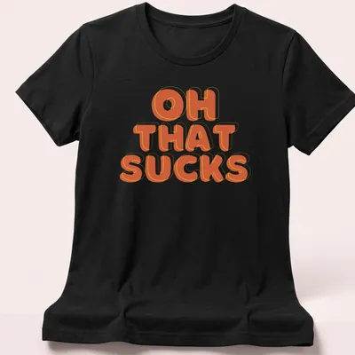 Retro-style t-shirt with orange and yellow text saying 'OH THAT SUCKS' — printed on a women's shirt