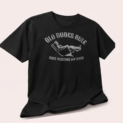 Vintage distressed t-shirt with a reclining man and humorous text about resting eyes — printed on a unisex t-shirt (angled view)