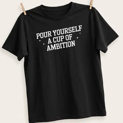 Inspirational t-shirt with bold text 'Pour Yourself A Cup Of Ambition' and a coffee cup illustration — printed on a unisex t-shirt