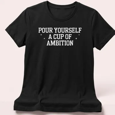 Inspirational t-shirt with bold text 'Pour Yourself A Cup Of Ambition' and a coffee cup illustration — printed on a women's shirt