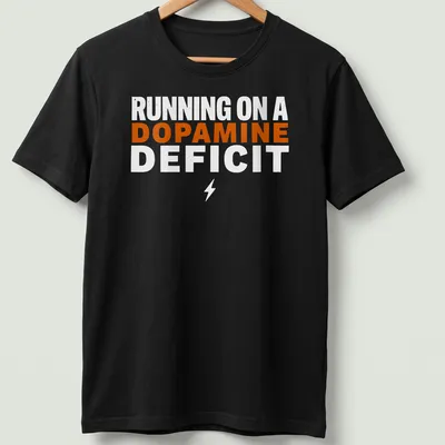 Bold typography humor t-shirt with the phrase 'RUNNING ON A DOPAMINE DEFICIT' in orange and white. — printed on a unisex t-shirt