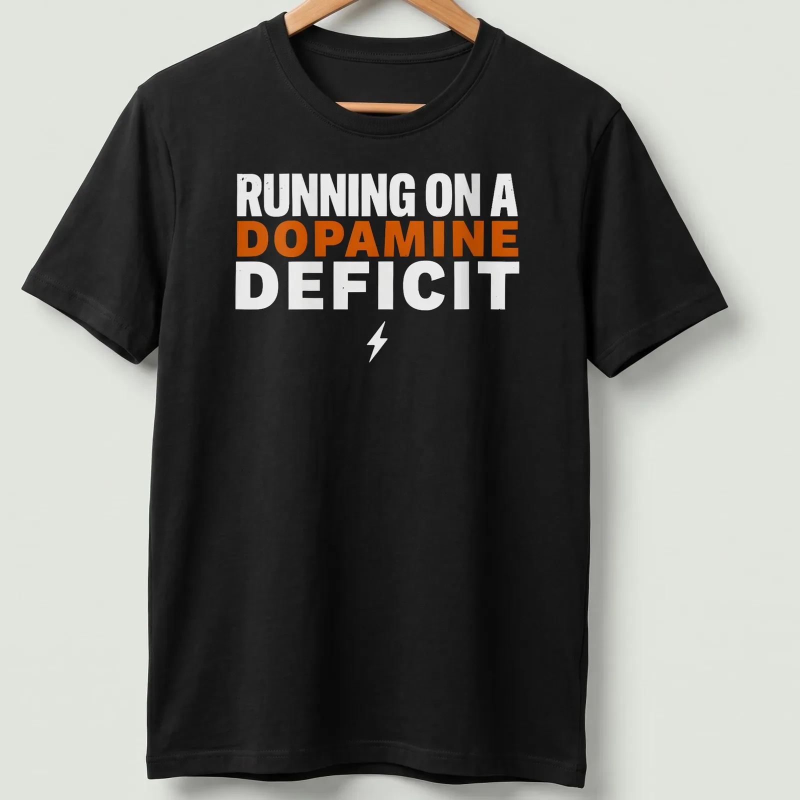 Bold typography humor t-shirt with the phrase 'RUNNING ON A DOPAMINE DEFICIT' in orange and white. — printed on a unisex t-shirt