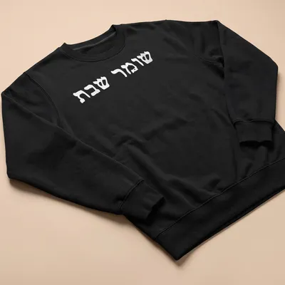 Minimalist Hebrew text reading Shomer Shabbat Shalom on white — printed on a unisex sweatshirt