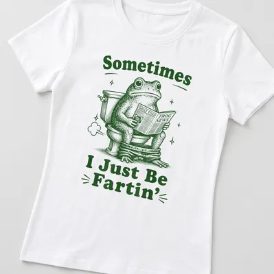Vintage illustration of a frog reading Daily Toad Frog News with humorous text — printed on a women's shirt