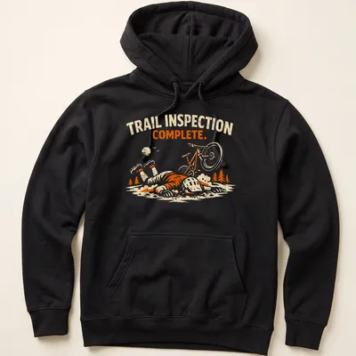 Playful illustration of a mountain biker with the text 'Trail Inspection Complete' in orange and cream tones. — printed on a unisex hoodie