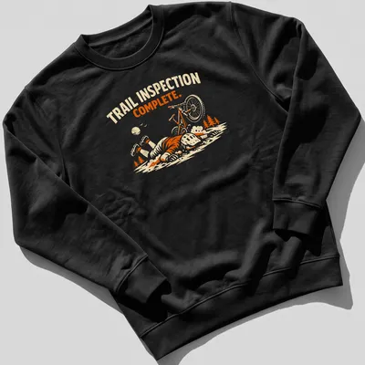 Playful illustration of a mountain biker with the text 'Trail Inspection Complete' in orange and cream tones. — printed on a unisex sweatshirt