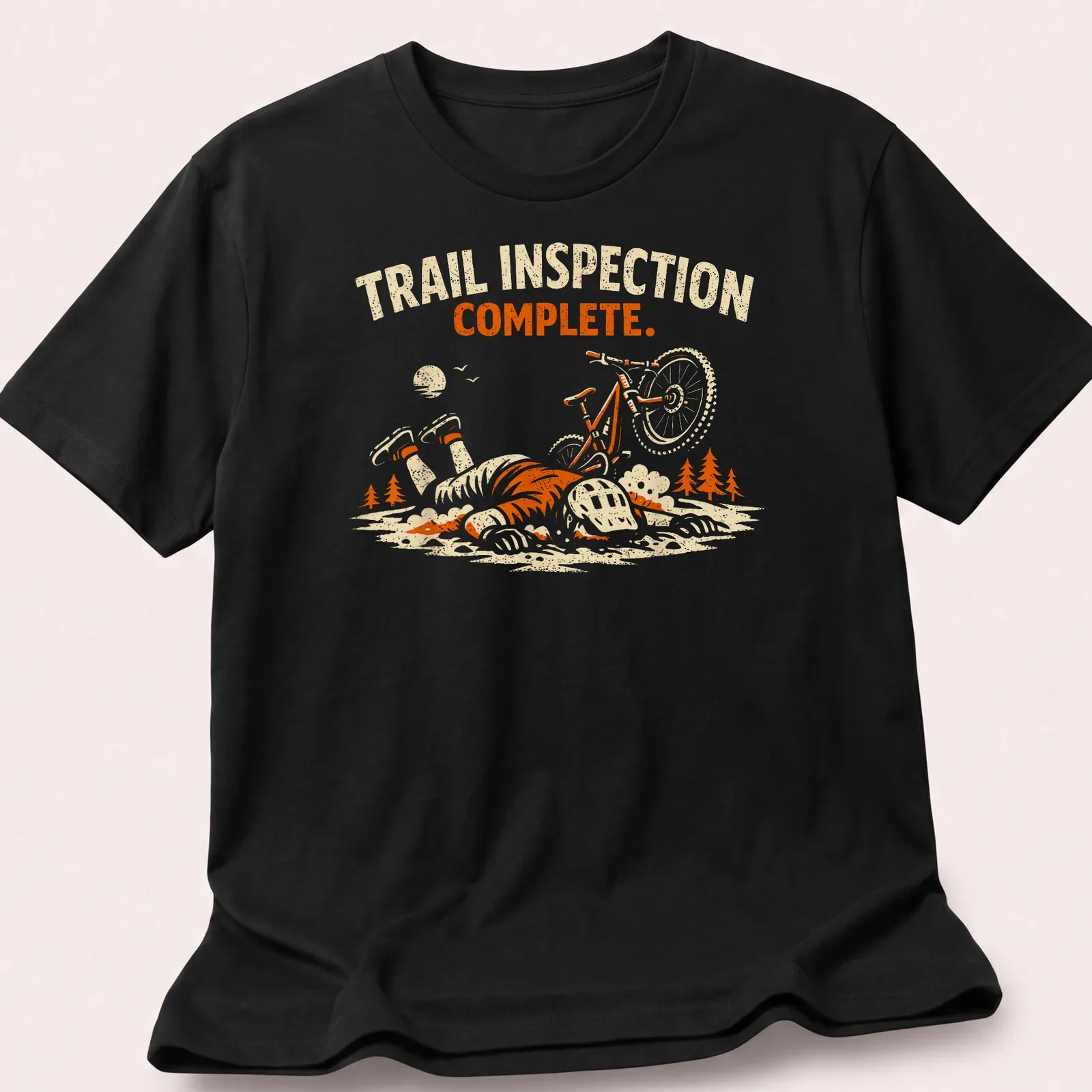 Playful illustration of a mountain biker with the text 'Trail Inspection Complete' in orange and cream tones. — printed on a unisex t-shirt