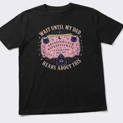 Whimsical T-shirt design featuring Ouija board and playful cats with humorous text.