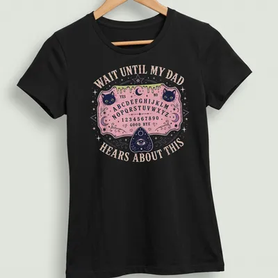 Whimsical T-shirt design featuring Ouija board and playful cats with humorous text. — printed on a women's shirt